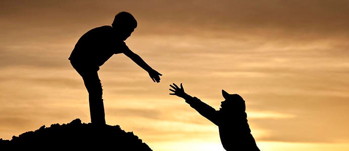 Dos personas ayudándose en una montaña al atardecer, simbolizando cómo en medio de la adicción y la recuperación alguien no puede sostenerlo todo solo y necesita apoyo para levantarse.
