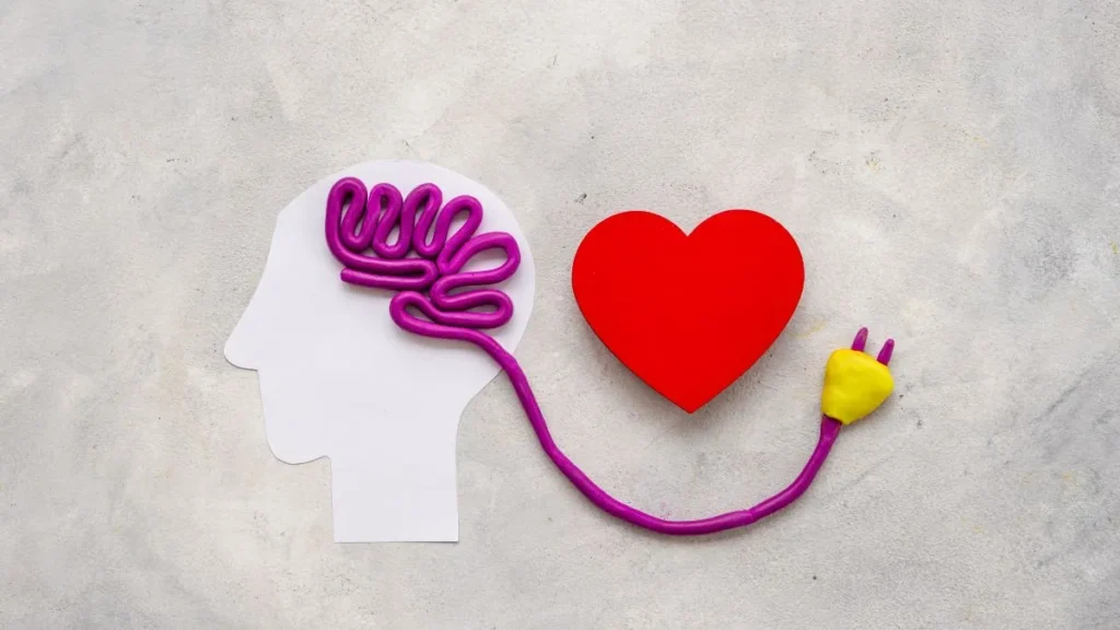 Imagen conceptual de una cabeza humana conectada a un corazón mediante un cable, simbolizando la relación entre la mente y las emociones. Representa cómo la ira,